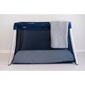 Portable travel cot with a gray blanket on a white background