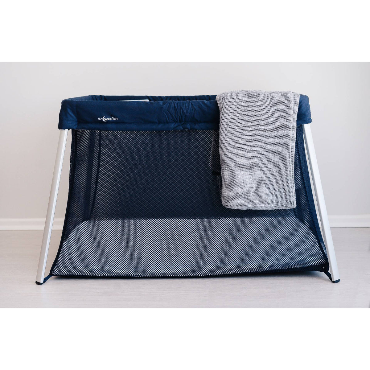 Navy Portable crib with a gray blanket on a white background