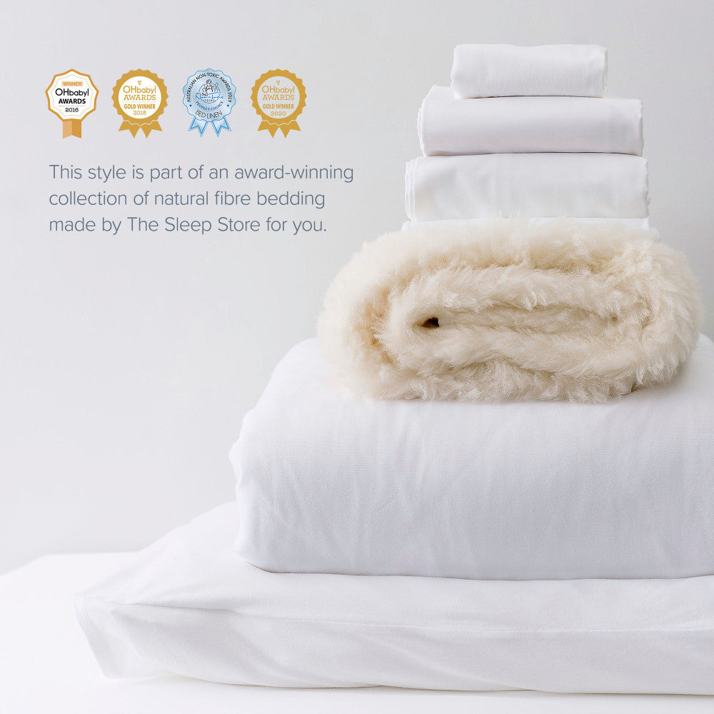 White bedding set with a fluffy white throw on a light gray background, featuring awards from The Sleep Store.