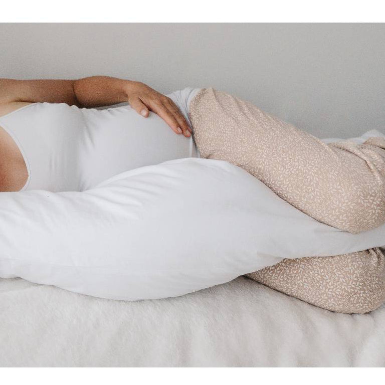 Person lying on a bed with a white comforter and beige pants.
