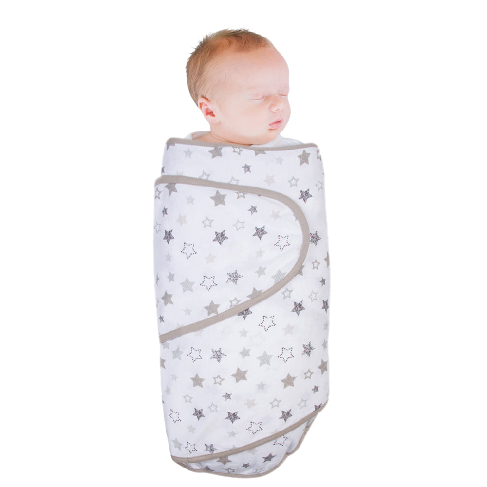 Baby wrapped in a miracle blanket swaddle with white/grey stars and grey piping on a white background