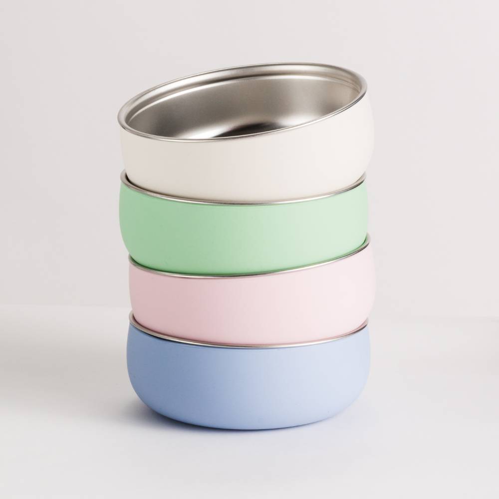 Stack of colorful silicone and stainless steel toddler bowls on a light gray background