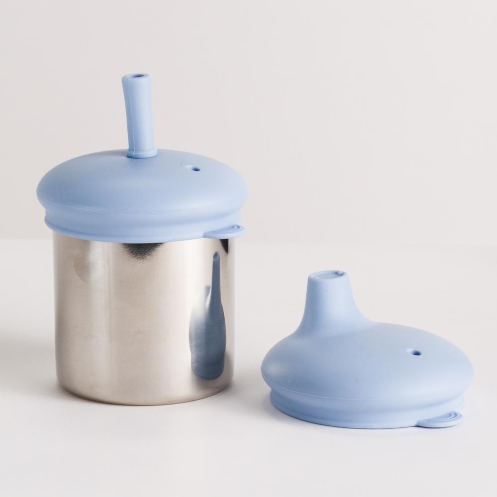 Stainless steel cup with blue silicone lid and straw on a light gray background