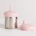 Nestling stainless steel cup with lid with and straw and another pink sippy cup lid on a white background