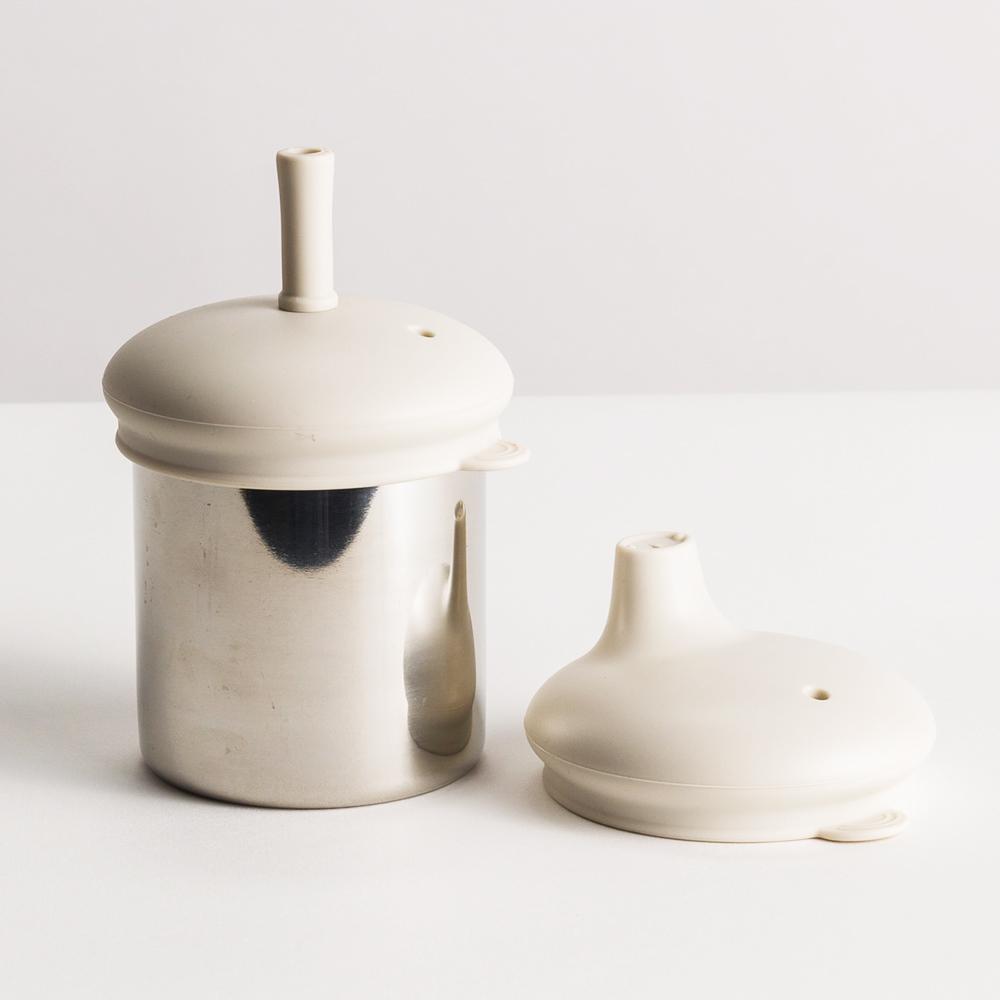 Nestling Stainless steel sippy cup with a straw lid and a sippy cup lid on a white background
