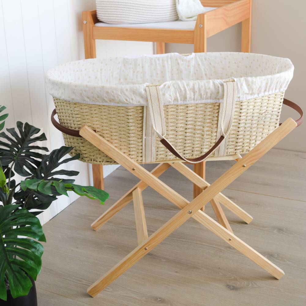 Moses Basket with wooden stand on a light wood floor.