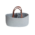 Grey cotton woven basket with brown faux leather handles and striped inner on a white background