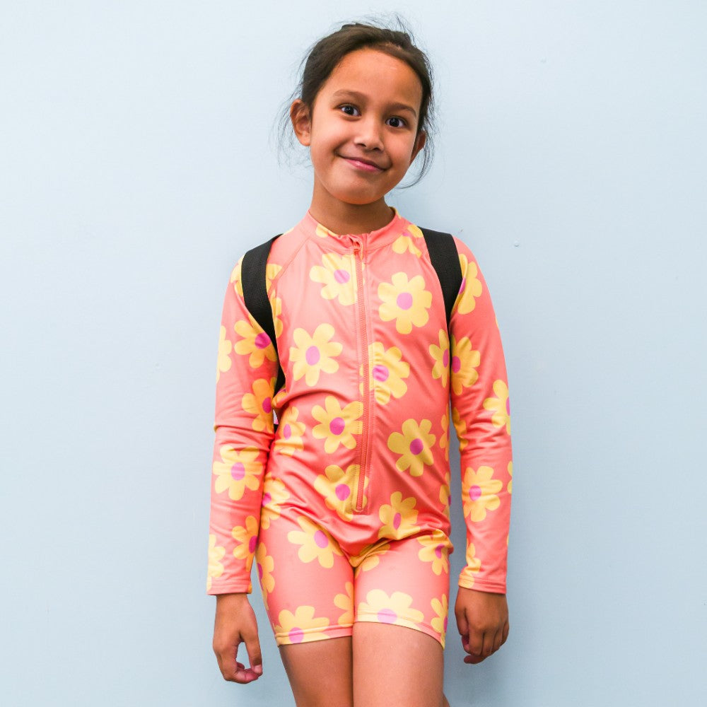 Child wearing a pink floral swimsuit against a light blue background