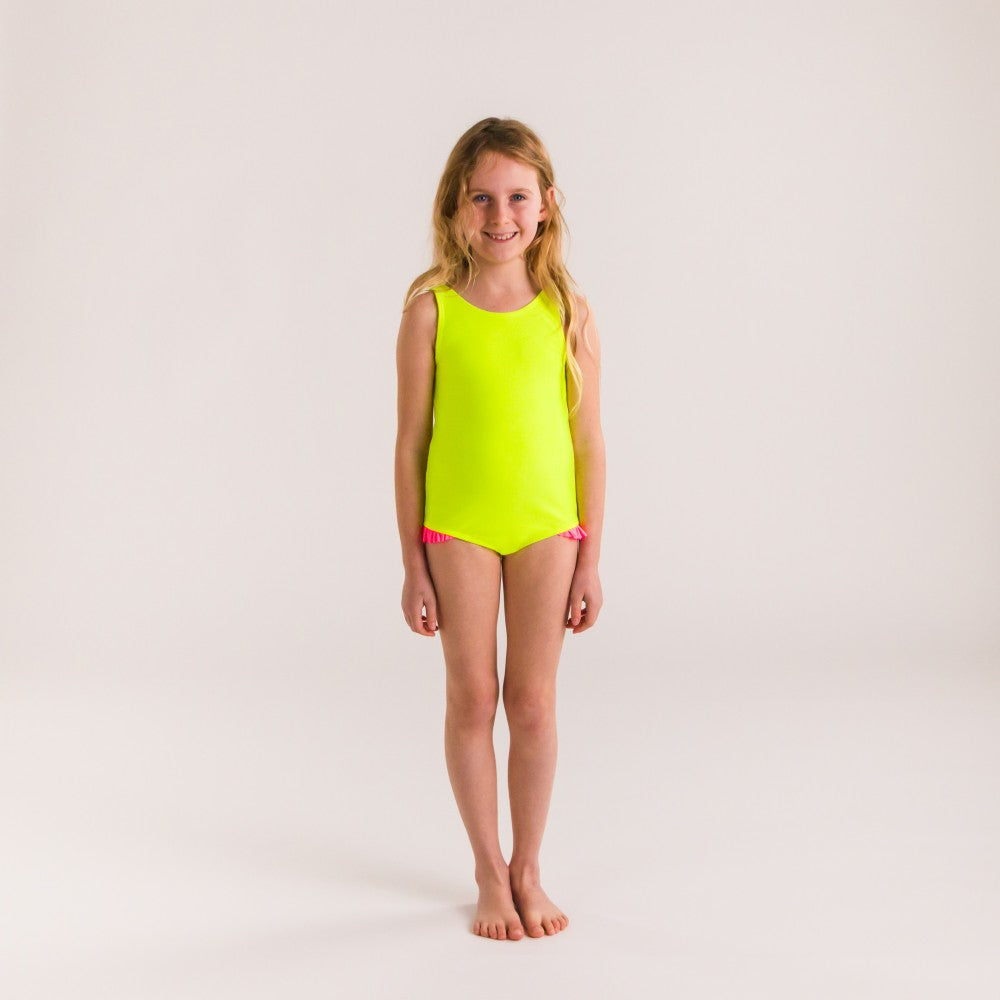 Young girl wearing a bright yellow swimsuit on a plain background