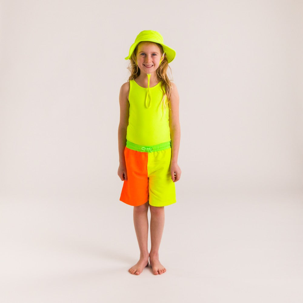 Child wearing a bright yellow swimsuit and orange shorts with a matching hat on a white background