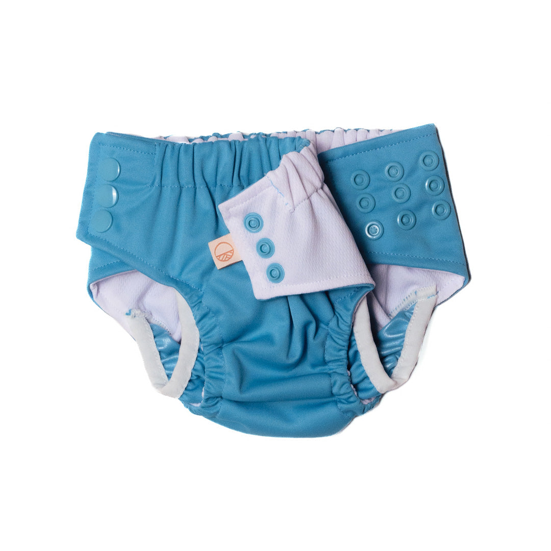 Rows of snaps on a blue Nestling swim nappy with white buttons on a white background