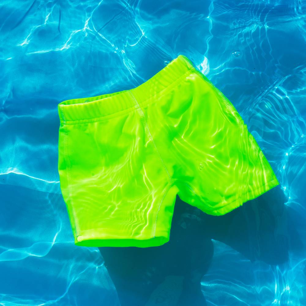 Neon green swim jammers floating in clear blue water