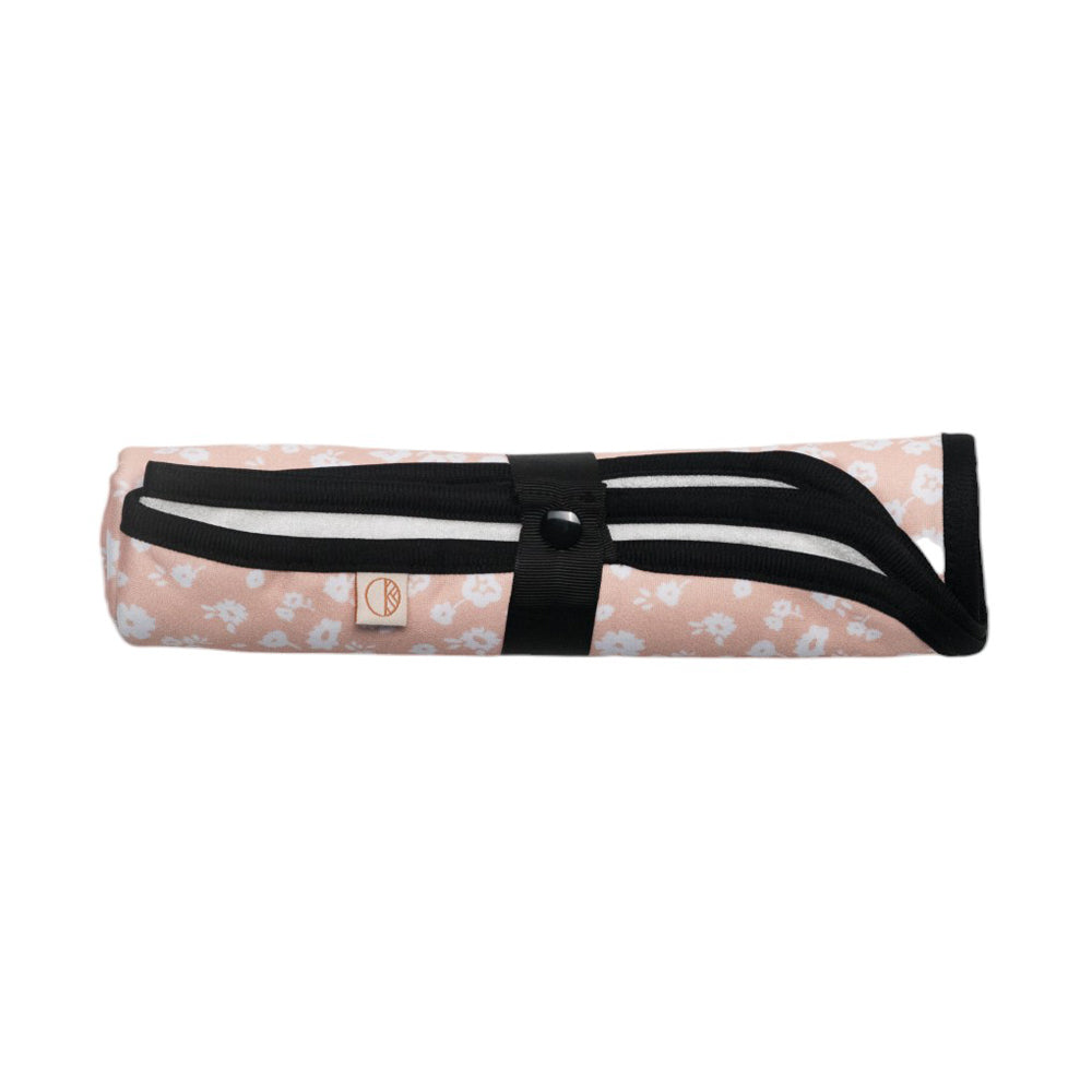 Roll-up change mat with floral pattern and black strap on a white background