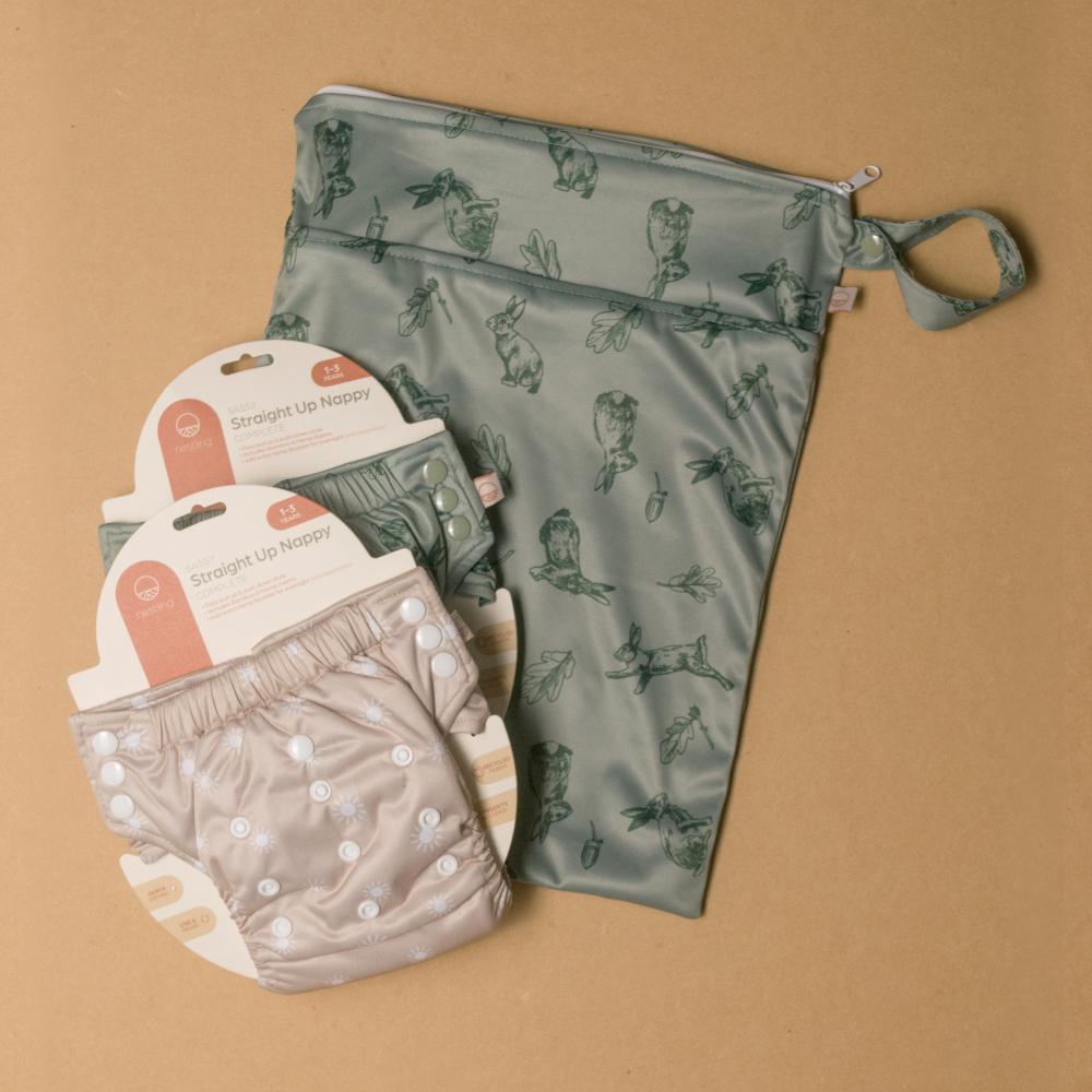 two reusable cloth toddler pull-ups and green patterned bag on a brown background