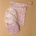 Set of pink floral-patterned baby products including a wet bag,3 cloth nappies on a brown background.