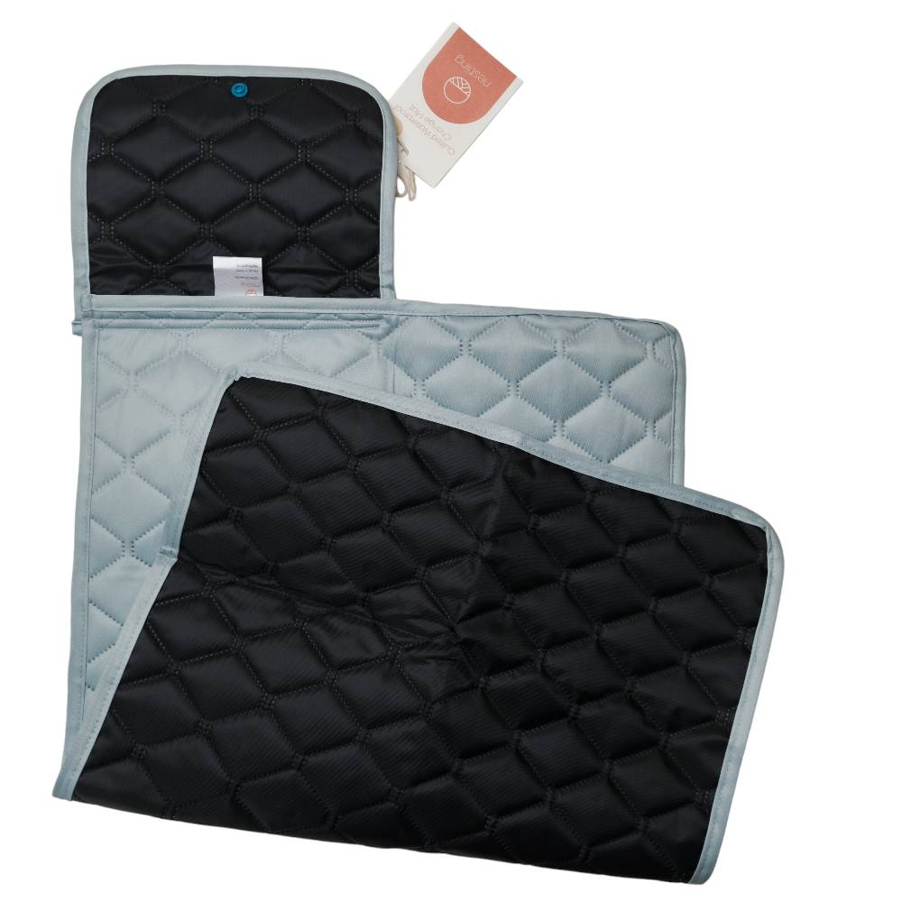 Black quilted change mat with sage green border and tag on a white background