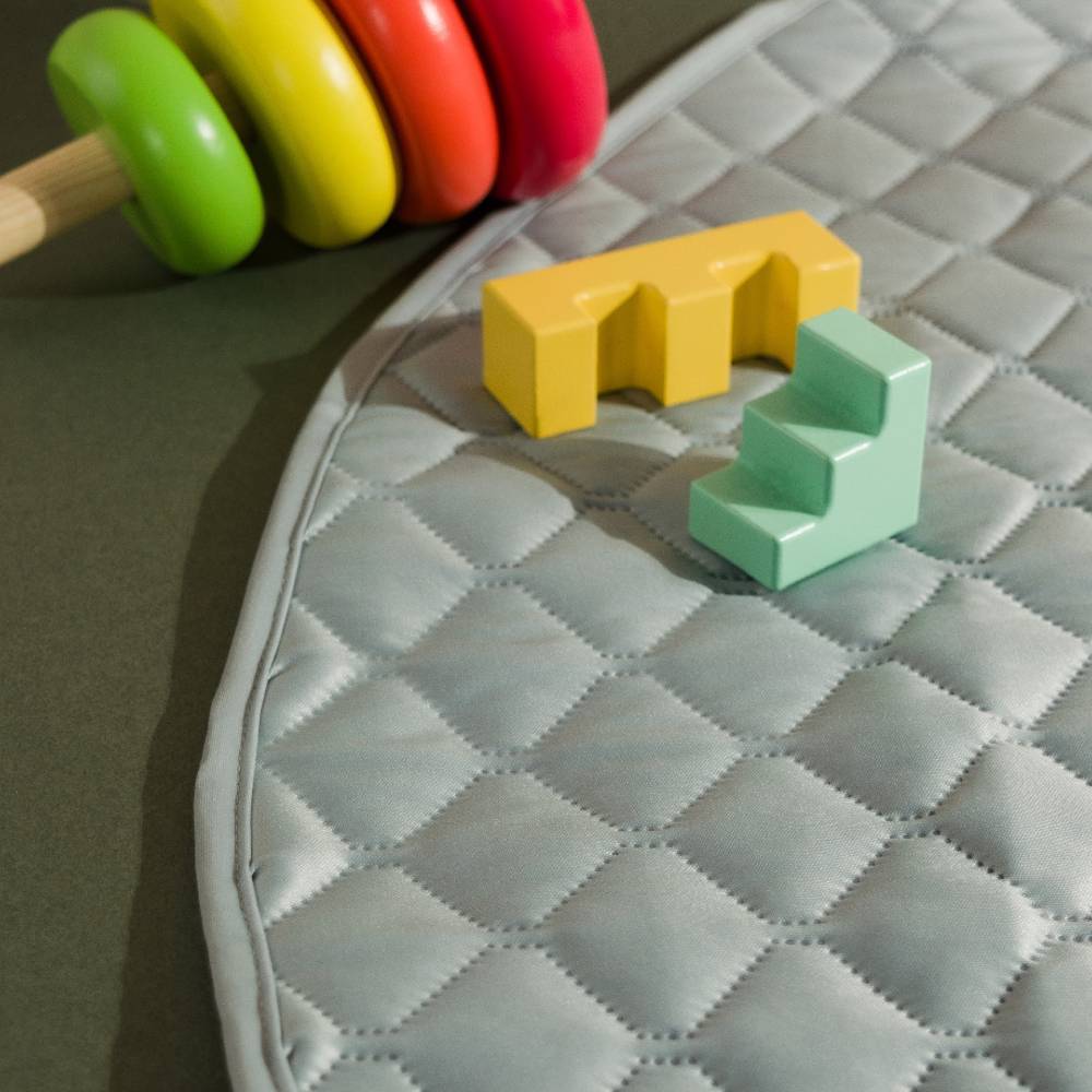 sage green waterproof children's play mat with wooden toys on green floor
