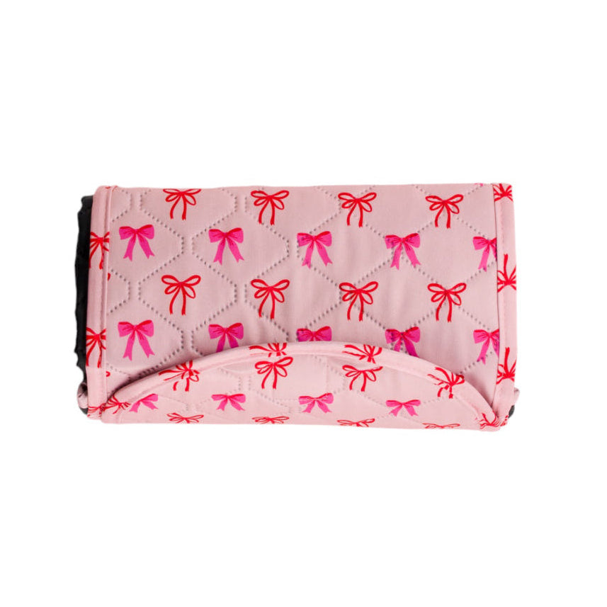 Bow print waterproof kids play mat folded up on white background

