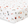 Close-up of white cotton muslin fitted sheet with mushroom pattern on a bed with a white background