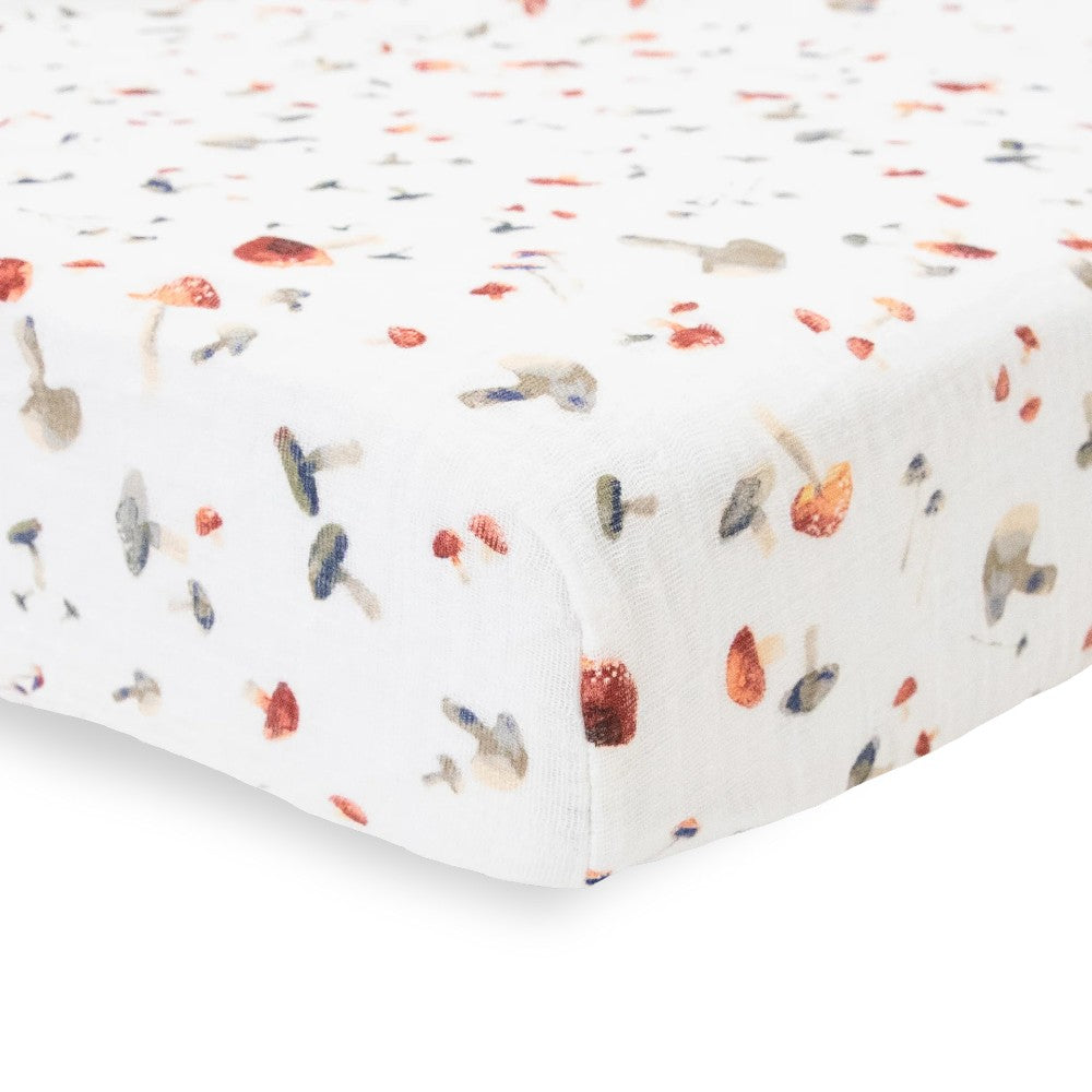 Close-up of white cotton muslin fitted sheet with mushroom pattern on a bed with a white background