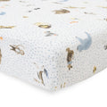 Close-up of white cotton muslin fitted sheet with blue dots and animal pattern on a bed with a white background