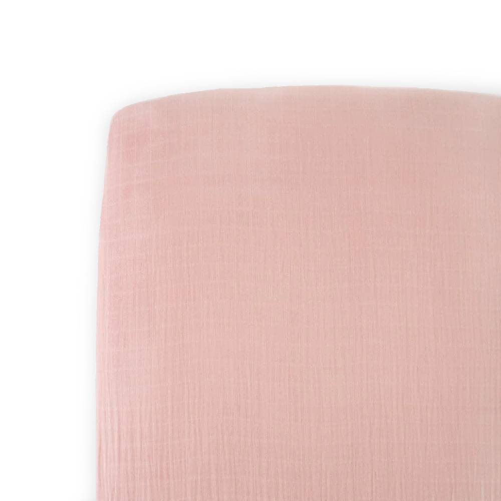 cotton muslin pink fitted sheet on a bed with a white background