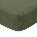 Close-up of green textured muslin cotton fitted sheet on a white background