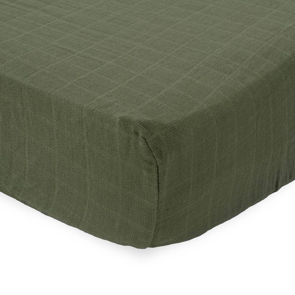 Close-up of green textured muslin cotton fitted sheet on a white background