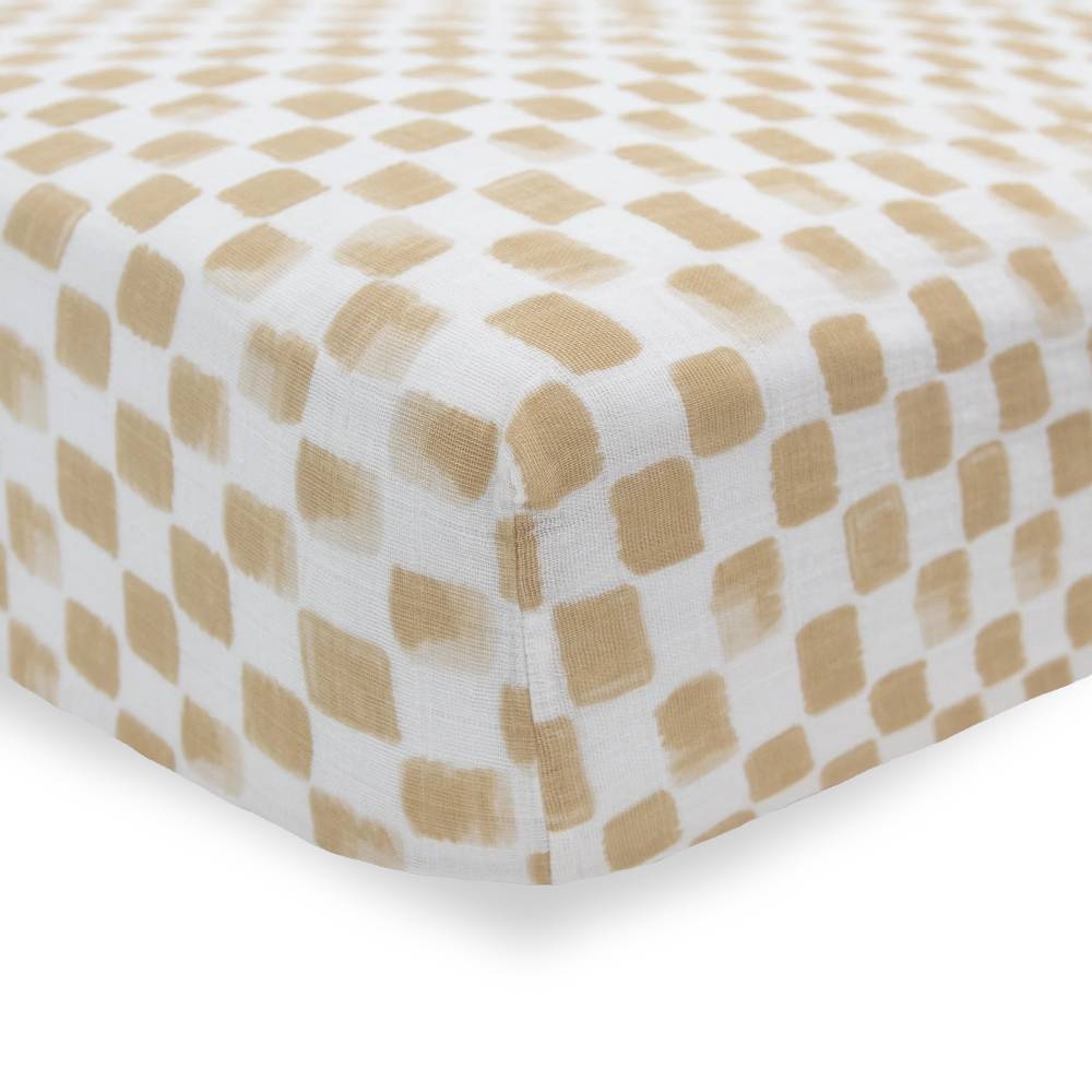 Close up of cotton muslin fitted sheet white and beige checkered pattern on a white background