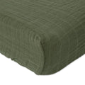 Little unicorn cotton muslin changing pad cover in a fern green colour on a bed with white background