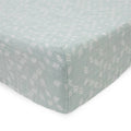 Little unicorn cotton muslin changing pad cover in a light green/blue with white pattern on a bed with white background