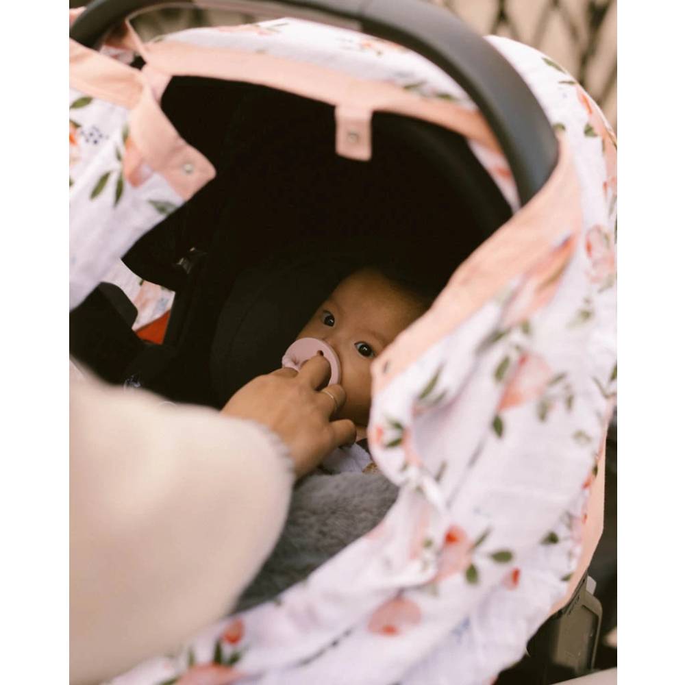Close-up of baby in a car seat with floral capsule cover 