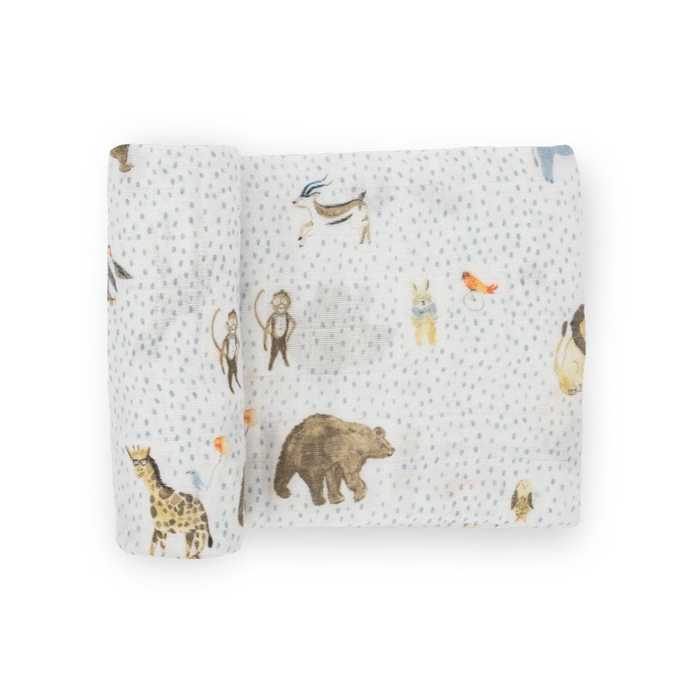 A white cotton muslin swaddle blanket with blue dots and animal designs on a white background