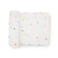 A white cotton muslin swaddle blanket with colourful dots patterns on a white background