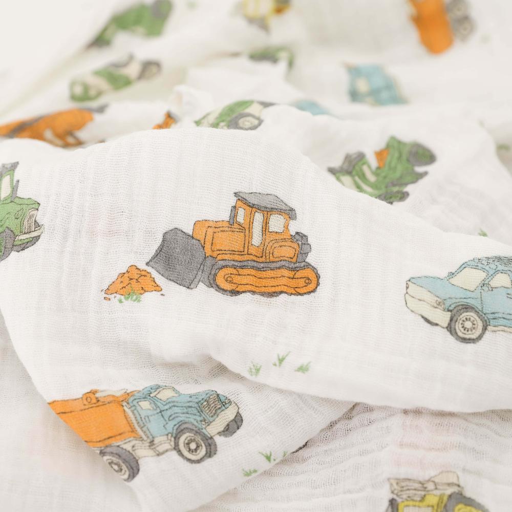 Close-up on baby muslin swaddle blanket with construction vehicle pattern on a white background
