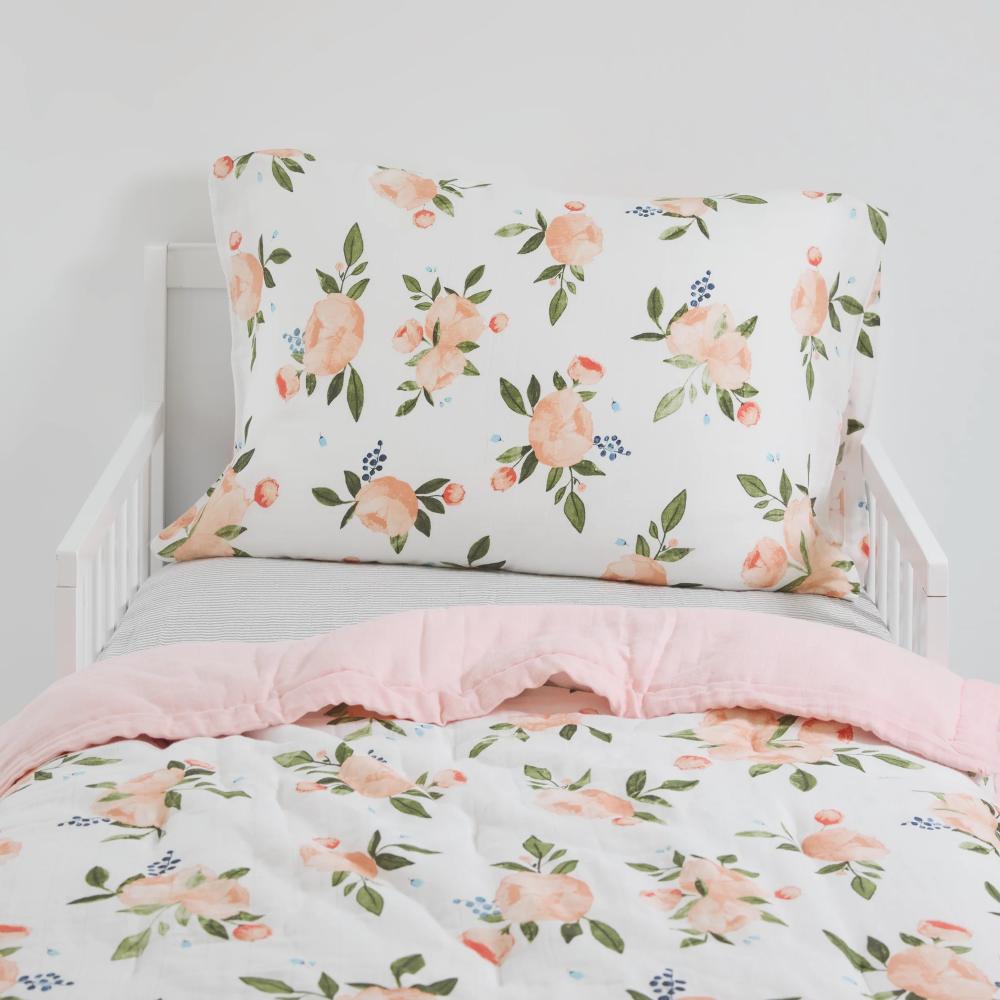 Floral bedding set with water colour roses in pink and green accents on a white bed.