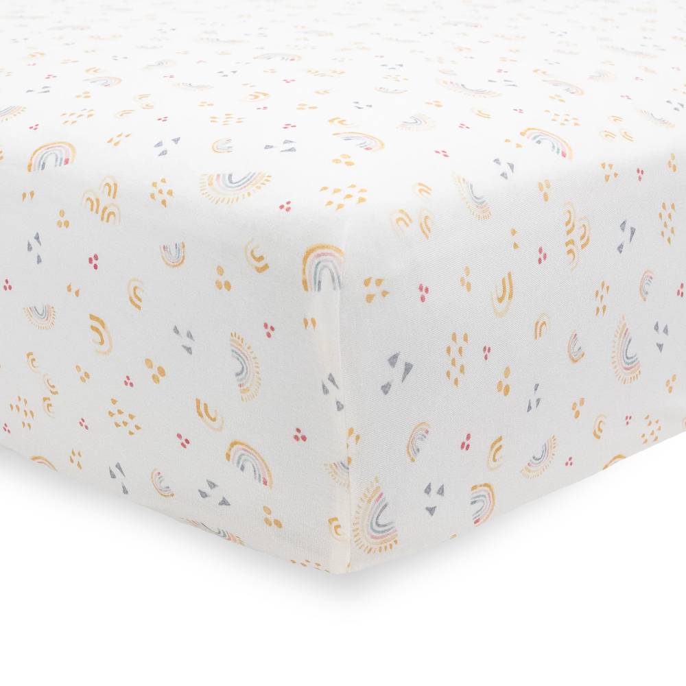 White fitted cot sheet with rainbow and cloud pattern on a white background