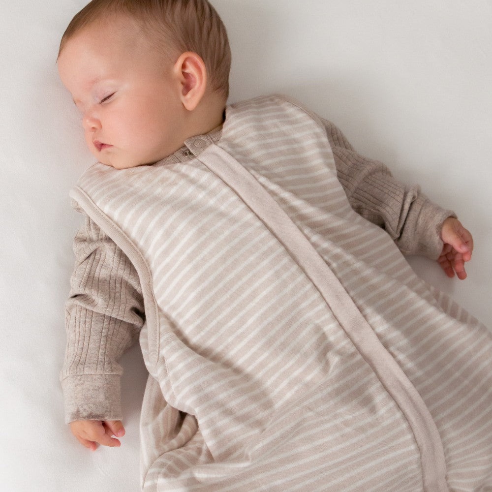 Baby sleeping in a striped baby sleeping bags on a white background