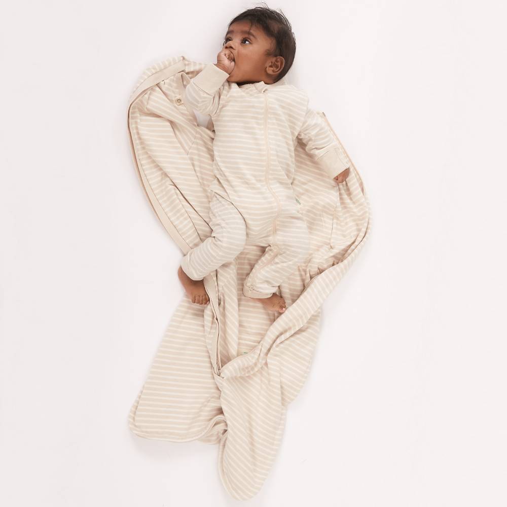 Baby wrapped in a beige sleeping bag on a white background