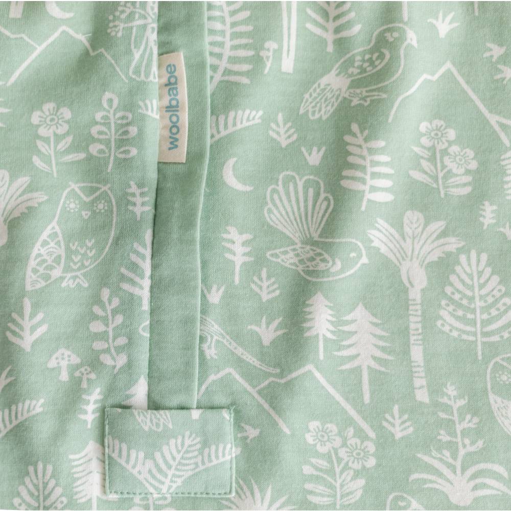 Green fabric with white nature-themed patterns and 'woolbabe' label.