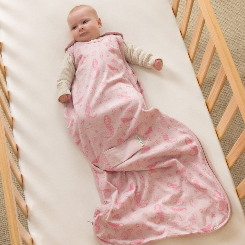 Baby lying in a crib with a pink sleeping bag wearable blanket
