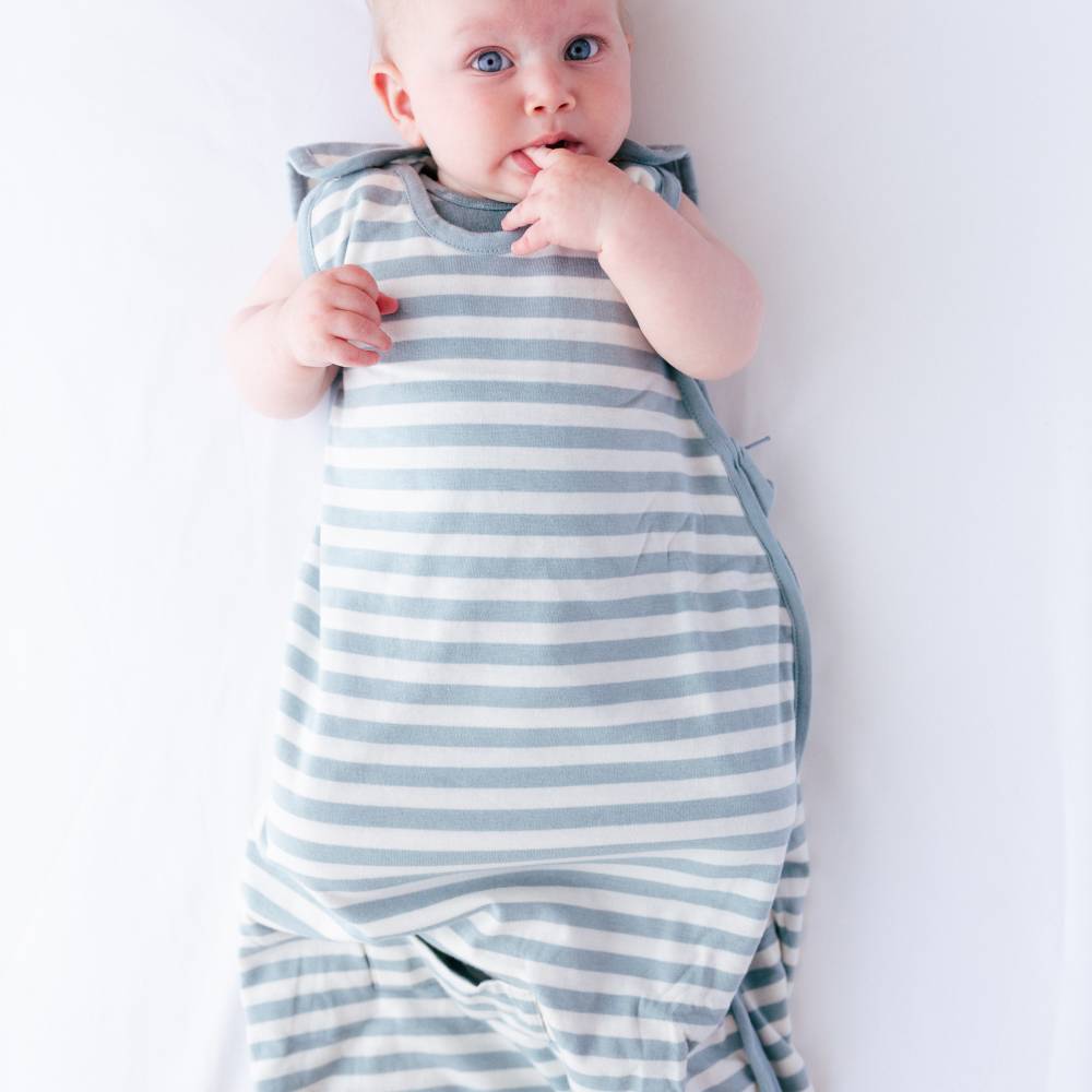 Baby wrapped in a blue and white striped sleeping bag on a plain background