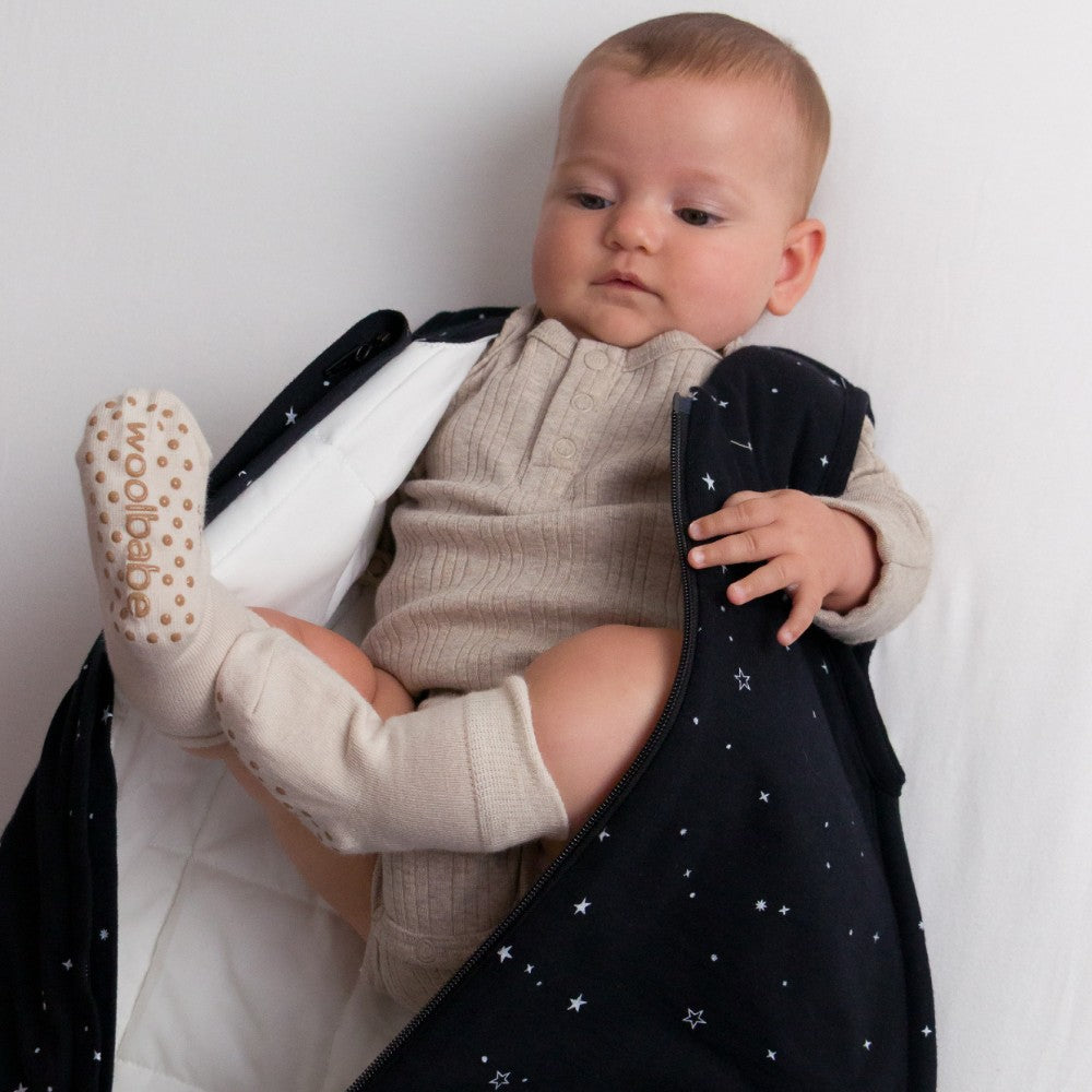 Baby wearing a dark blue coat with star patterns, holding a white blanket with 'Babycalin' branding.