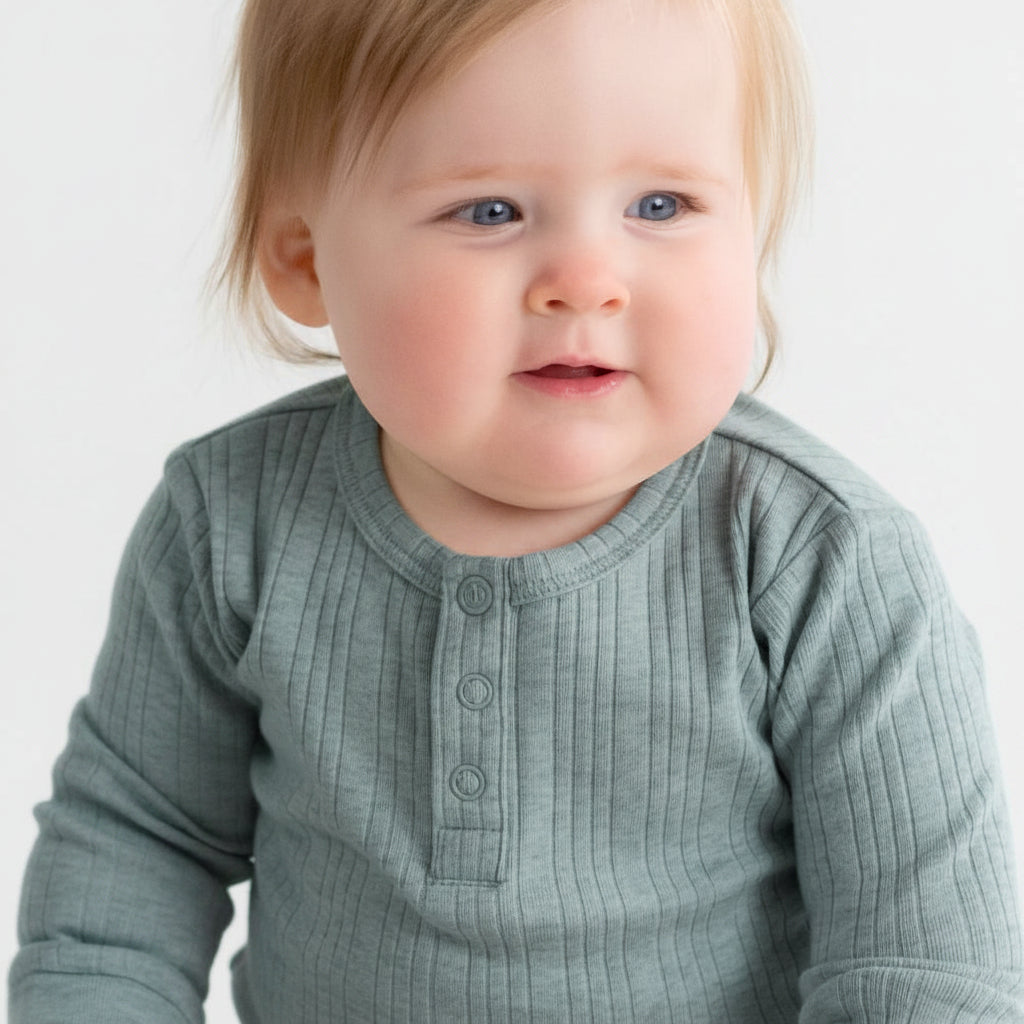 Baby wearing a tide long-sleeve shirt against a white background