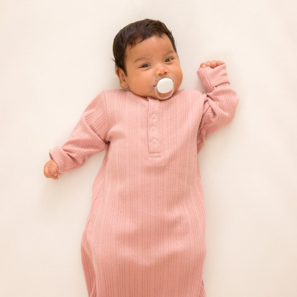 Baby in a pink rib baby nightie  on a white background
