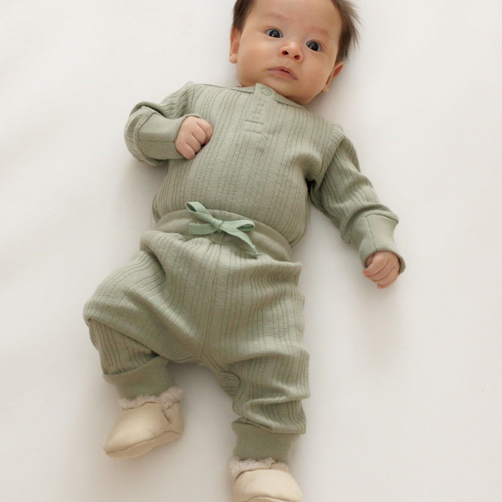 Baby wearing a green outfit on a white background