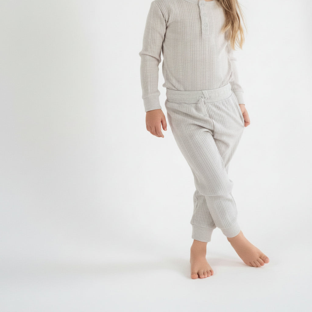 Child wearing a cream merino woolbabe pants on a white background