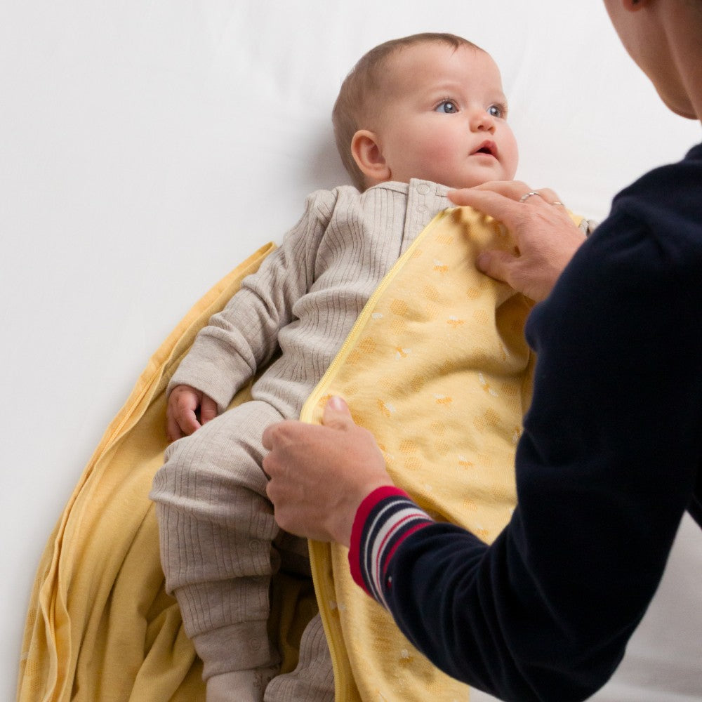 Baby being held by an adult with a yellow blanket