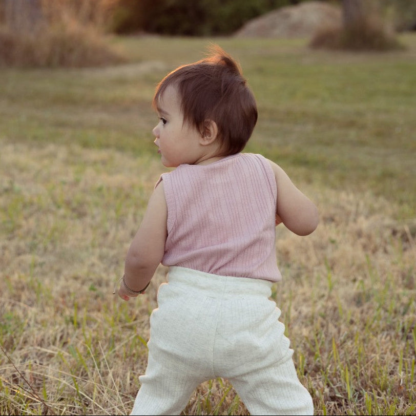 Child walking in a grassy field with trees in the background