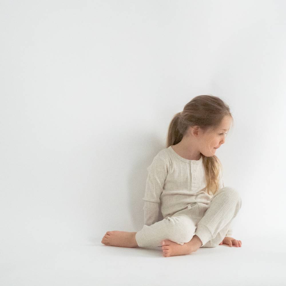 Young girl sitting on a white floor against a white wall